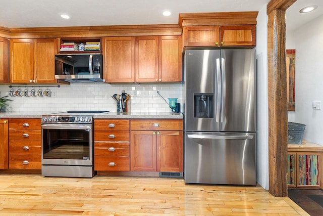 kitchen with brown cabinets, light wood finished floors, stainless steel appliances, recessed lighting, and tasteful backsplash