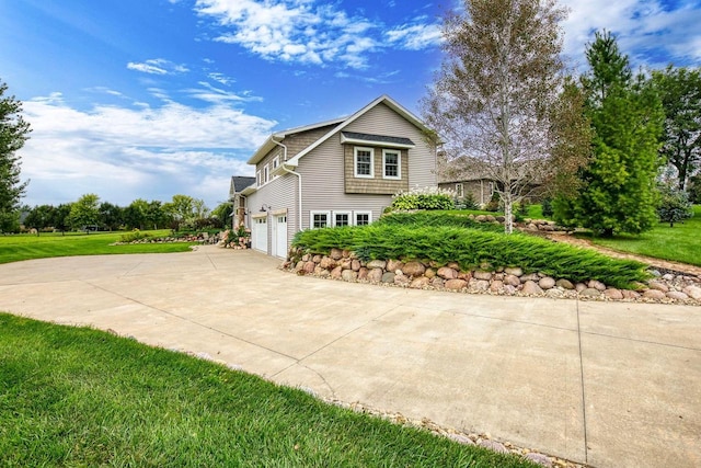 view of side of property featuring driveway, an attached garage, and a lawn