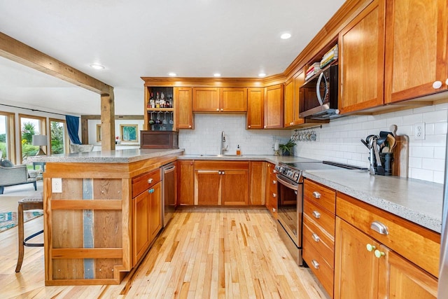 kitchen with light wood finished floors, brown cabinetry, appliances with stainless steel finishes, open shelves, and a sink