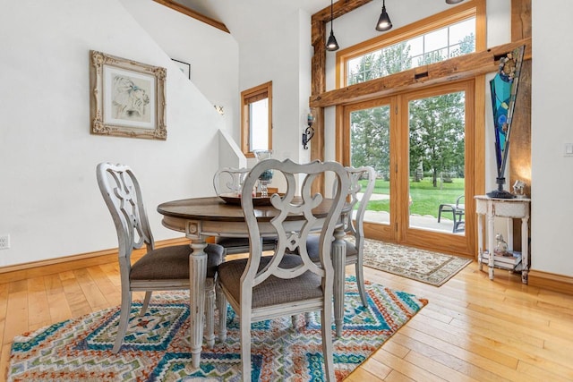 dining area with a towering ceiling, baseboards, and hardwood / wood-style flooring