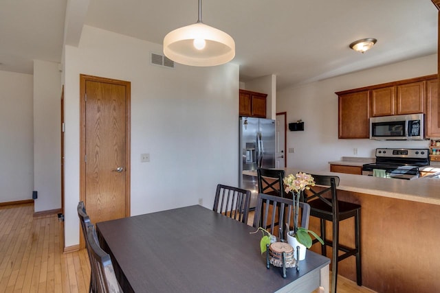 dining area with visible vents, light wood-style flooring, and baseboards