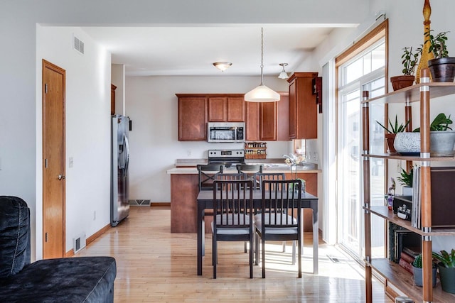 kitchen with a peninsula, light wood-style flooring, visible vents, and stainless steel appliances