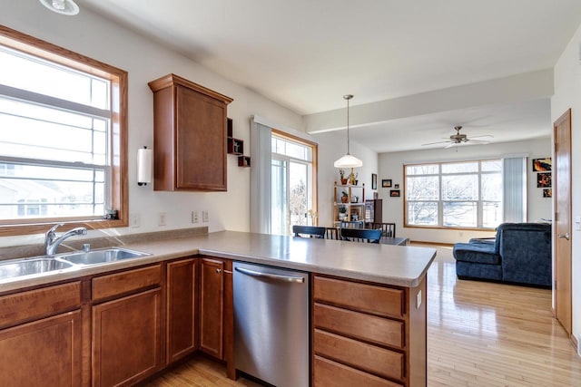 kitchen with a sink, stainless steel dishwasher, a peninsula, and a wealth of natural light