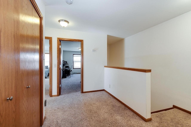 hall featuring an upstairs landing, carpet, and baseboards