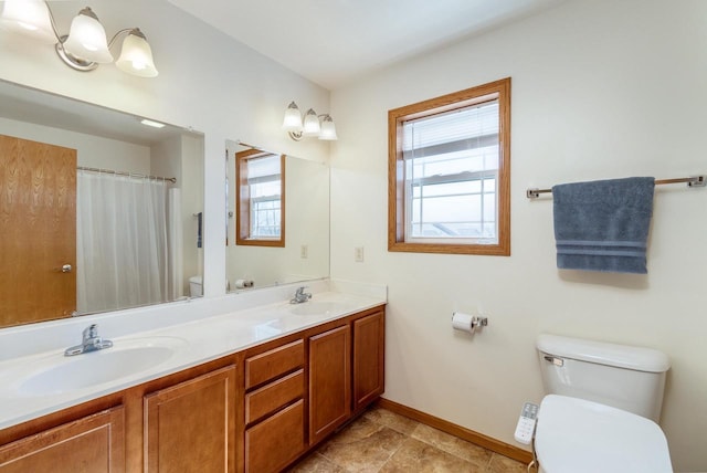 full bath with double vanity, toilet, baseboards, and a sink