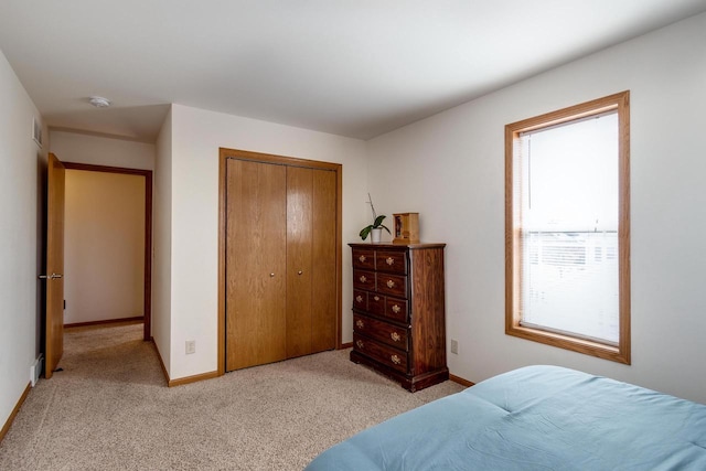 bedroom featuring light carpet, baseboards, and a closet