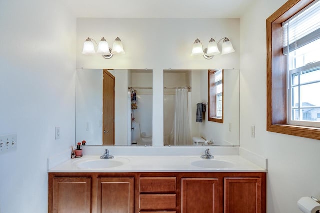 bathroom with curtained shower, double vanity, toilet, and a sink