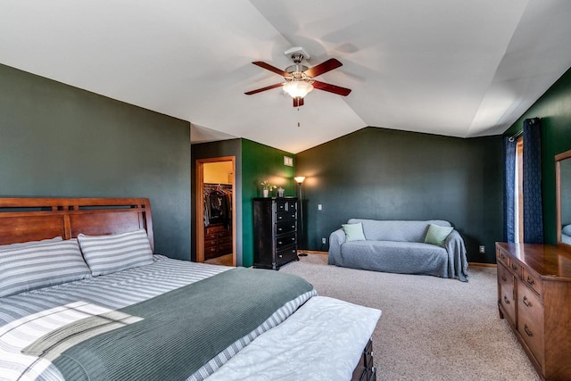 bedroom with a ceiling fan, vaulted ceiling, a closet, light carpet, and a walk in closet