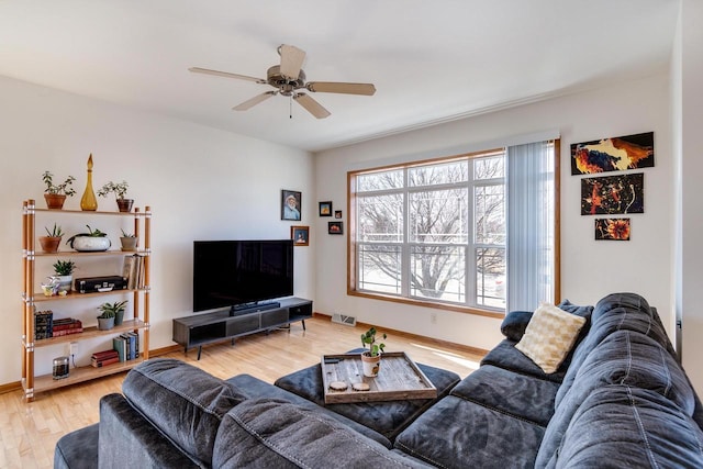 living area featuring light wood finished floors, visible vents, baseboards, and a ceiling fan