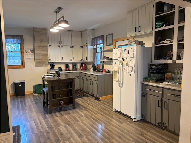 kitchen featuring white refrigerator with ice dispenser, open shelves, wood finished floors, and gray cabinetry