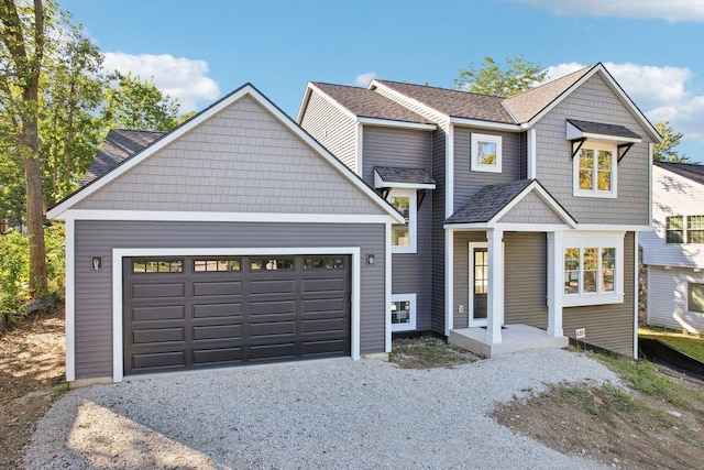 view of front of home with a garage, roof with shingles, and gravel driveway