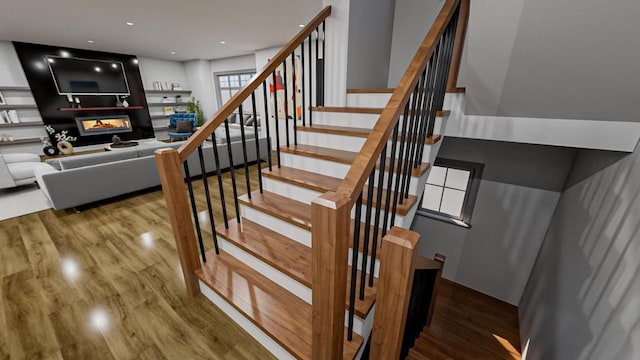 staircase with recessed lighting, a multi sided fireplace, and wood finished floors