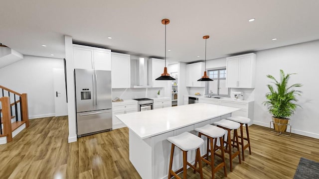 kitchen with a center island, light wood finished floors, light countertops, white cabinets, and stainless steel fridge with ice dispenser