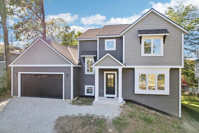 view of front of property featuring a shingled roof, an attached garage, and gravel driveway