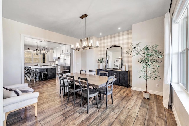 dining room featuring an inviting chandelier, baseboards, wood finished floors, and recessed lighting