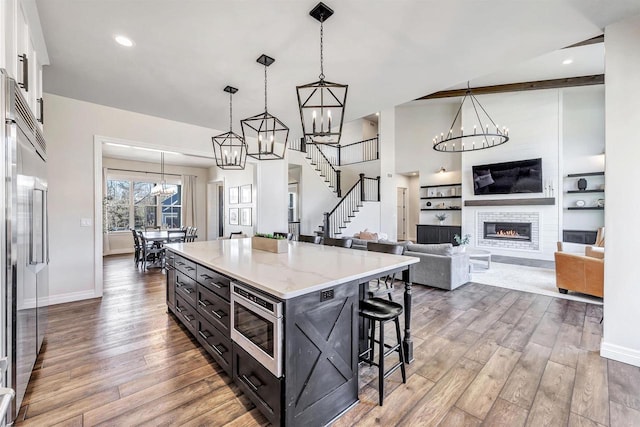 kitchen featuring white cabinets, built in appliances, a kitchen bar, a fireplace, and a notable chandelier