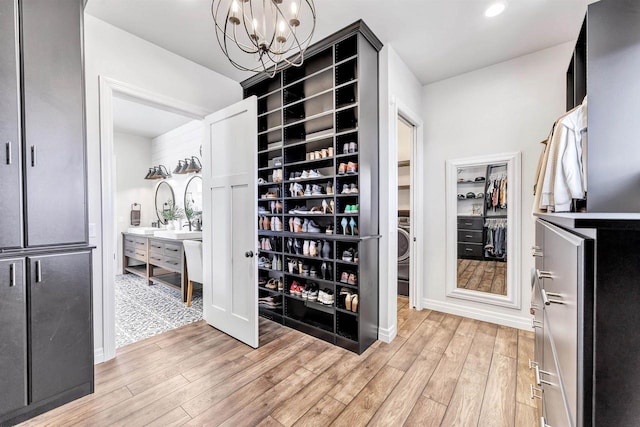 spacious closet featuring light wood-style flooring and an inviting chandelier