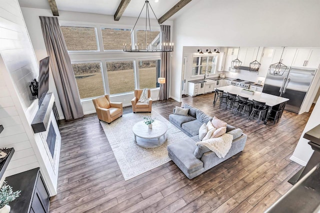 living room featuring an inviting chandelier, high vaulted ceiling, dark wood finished floors, and beamed ceiling