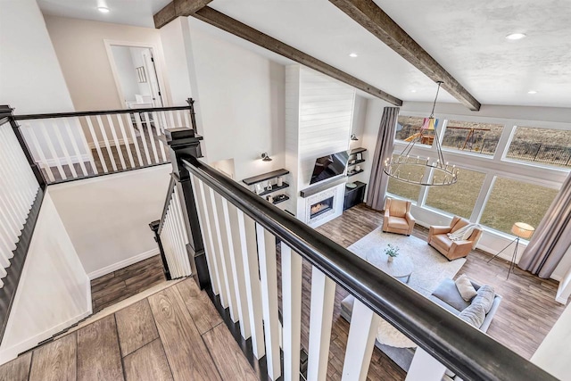 stairs featuring beam ceiling, recessed lighting, a glass covered fireplace, wood finished floors, and baseboards