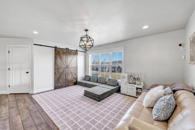 living area featuring a barn door, baseboards, wood finished floors, and recessed lighting