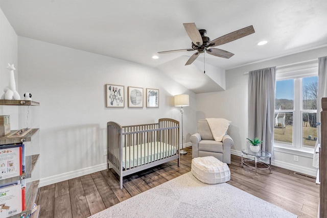 bedroom featuring recessed lighting, wood finished floors, visible vents, baseboards, and a nursery area