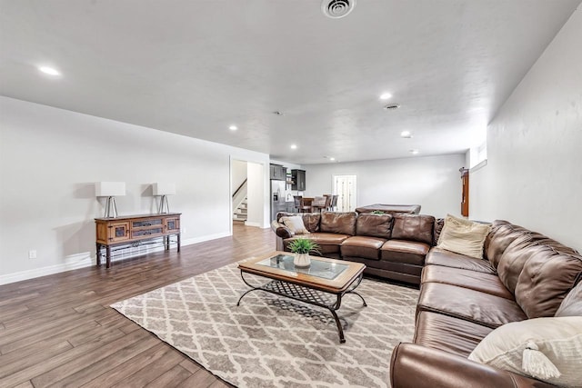 living area featuring stairway, light wood-style flooring, visible vents, and baseboards