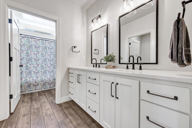 bathroom featuring double vanity, a shower with curtain, a sink, and wood finished floors