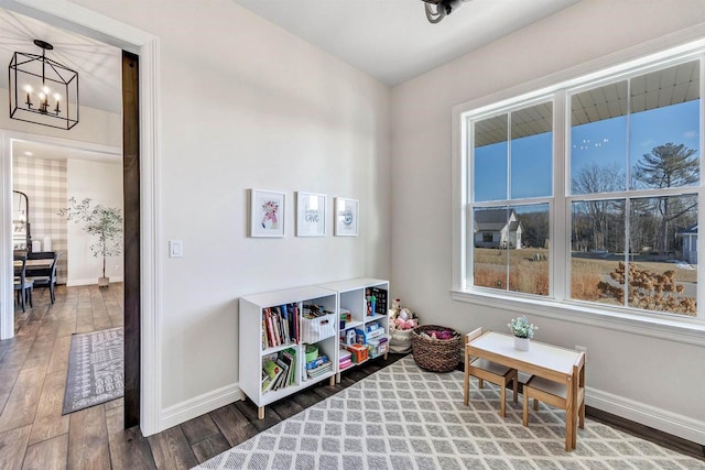 playroom with an inviting chandelier, wood finished floors, and baseboards