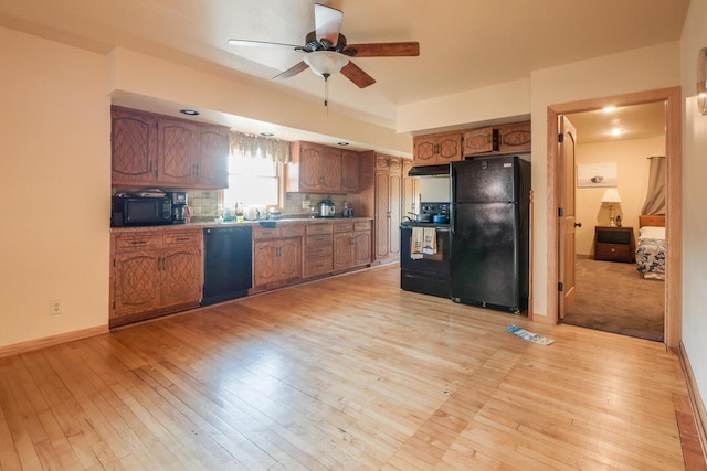 kitchen featuring light wood-type flooring, black appliances, brown cabinetry, and backsplash