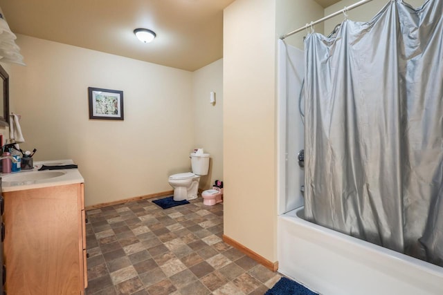 full bathroom with stone finish floor, vanity, toilet, and baseboards