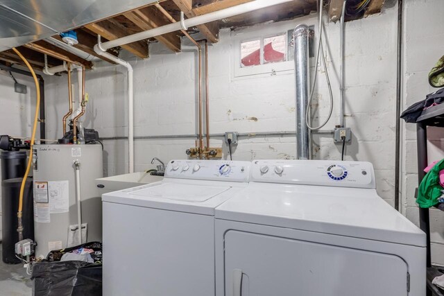 clothes washing area with washer and dryer, laundry area, water heater, and a sink