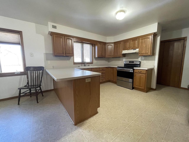 kitchen featuring under cabinet range hood, a peninsula, electric range, a sink, and light countertops