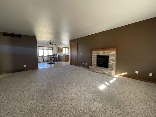 unfurnished living room featuring carpet floors, baseboards, a fireplace, and visible vents