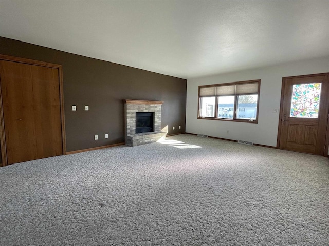 unfurnished living room with visible vents, baseboards, lofted ceiling, carpet floors, and a brick fireplace