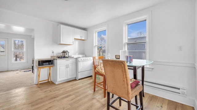 kitchen with a healthy amount of sunlight, white cabinetry, baseboard heating, and gas range gas stove