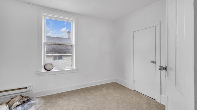 carpeted empty room with a baseboard radiator and baseboards