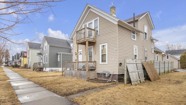 view of property exterior with a residential view, a chimney, fence, and a balcony