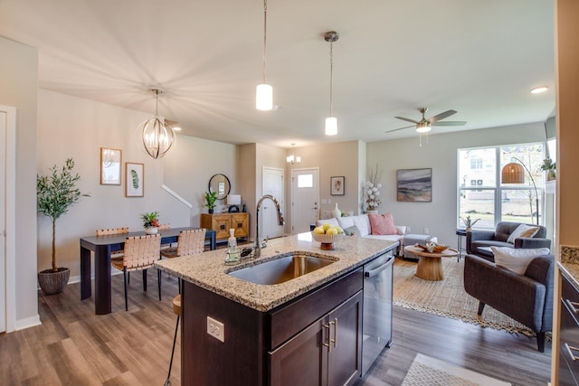 kitchen with dark wood-type flooring, open floor plan, dark brown cabinetry, a sink, and dishwasher