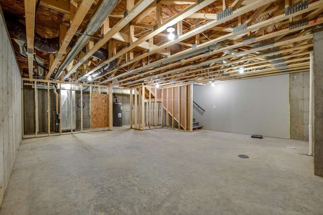 unfinished basement featuring stairway and electric water heater