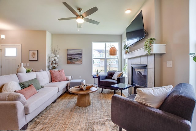 living area featuring wood finished floors, a tile fireplace, and a ceiling fan