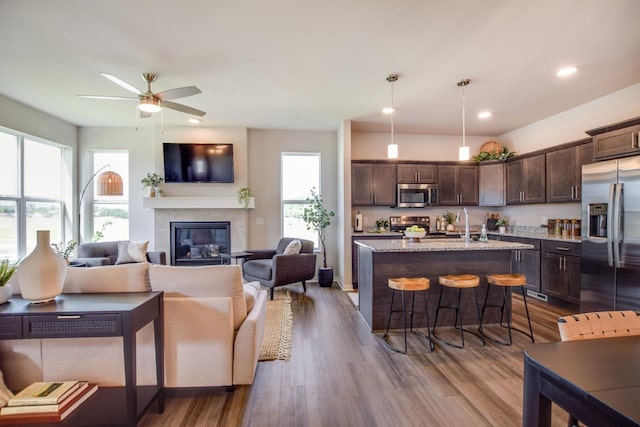 kitchen with dark brown cabinetry, dark wood-type flooring, a kitchen breakfast bar, open floor plan, and appliances with stainless steel finishes