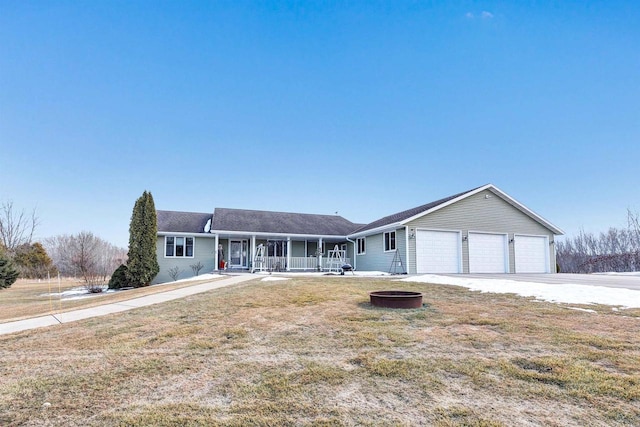 ranch-style home with driveway, an attached garage, a fire pit, and a front lawn