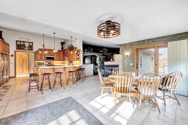 dining area with light tile patterned floors, vaulted ceiling, a fireplace, and baseboards