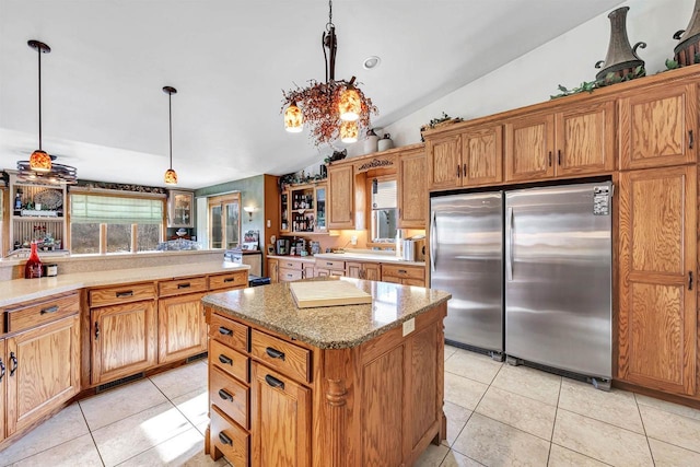 kitchen featuring a center island, pendant lighting, light tile patterned floors, lofted ceiling, and stainless steel refrigerator