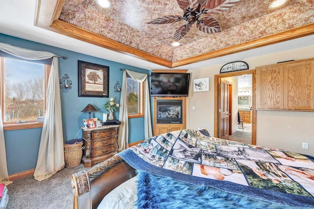 carpeted bedroom with baseboards and a raised ceiling