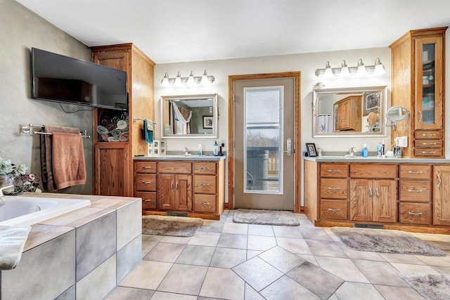 bathroom featuring tiled tub, tile patterned flooring, two vanities, and visible vents