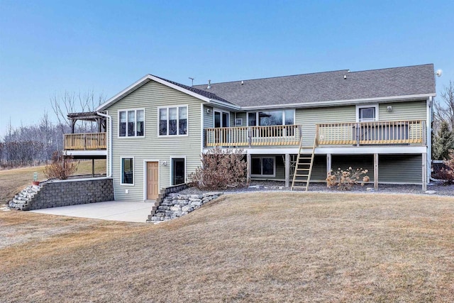 rear view of house with a yard, a shingled roof, a deck, and a patio