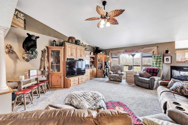 living area featuring light carpet, ceiling fan, vaulted ceiling, and decorative columns