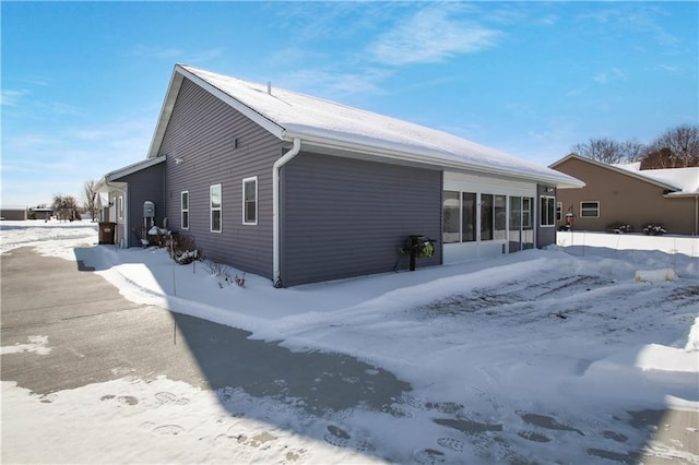 view of snowy exterior with a sunroom