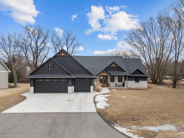 view of front of home with a shingled roof, stone siding, driveway, and an attached garage